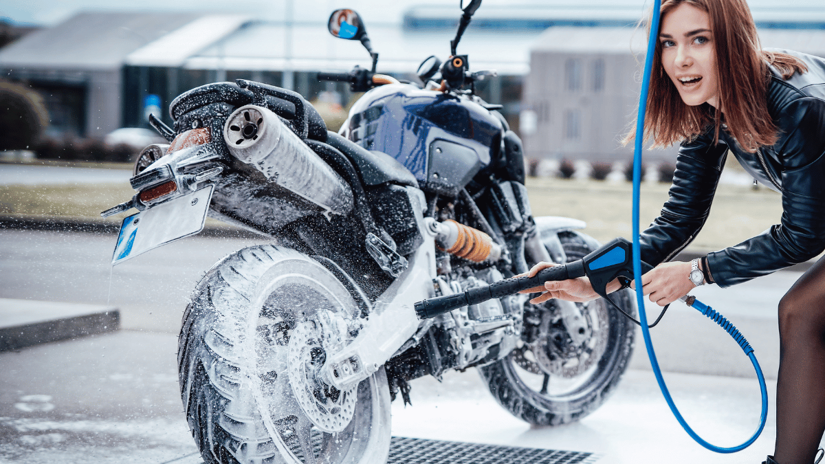 perempuan sedang mencuci motor dengan penyemprot air
